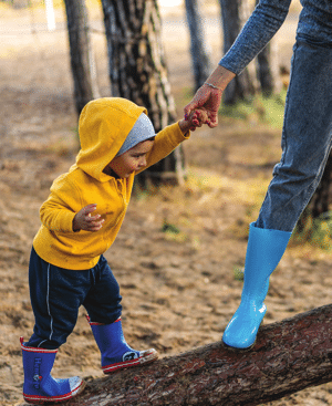 Viveka's story - mother holding her son's hand as they balance on a fallen log