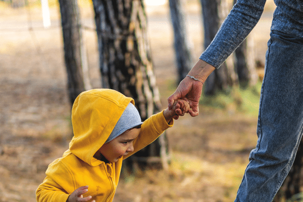 Viveka's story - mother holding her son's hand as they balance on a fallen log